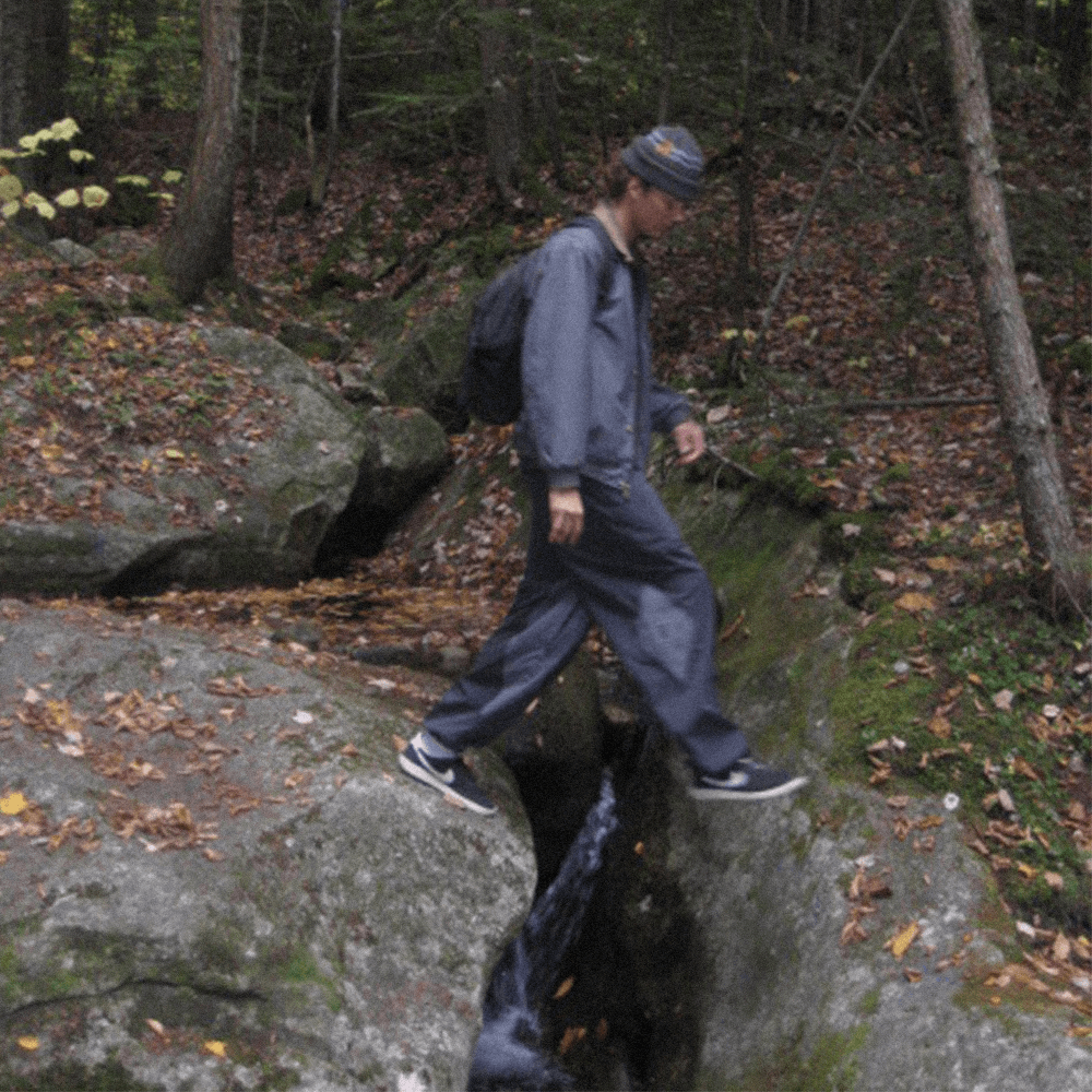 a person walking over a river in a baggy snowpants