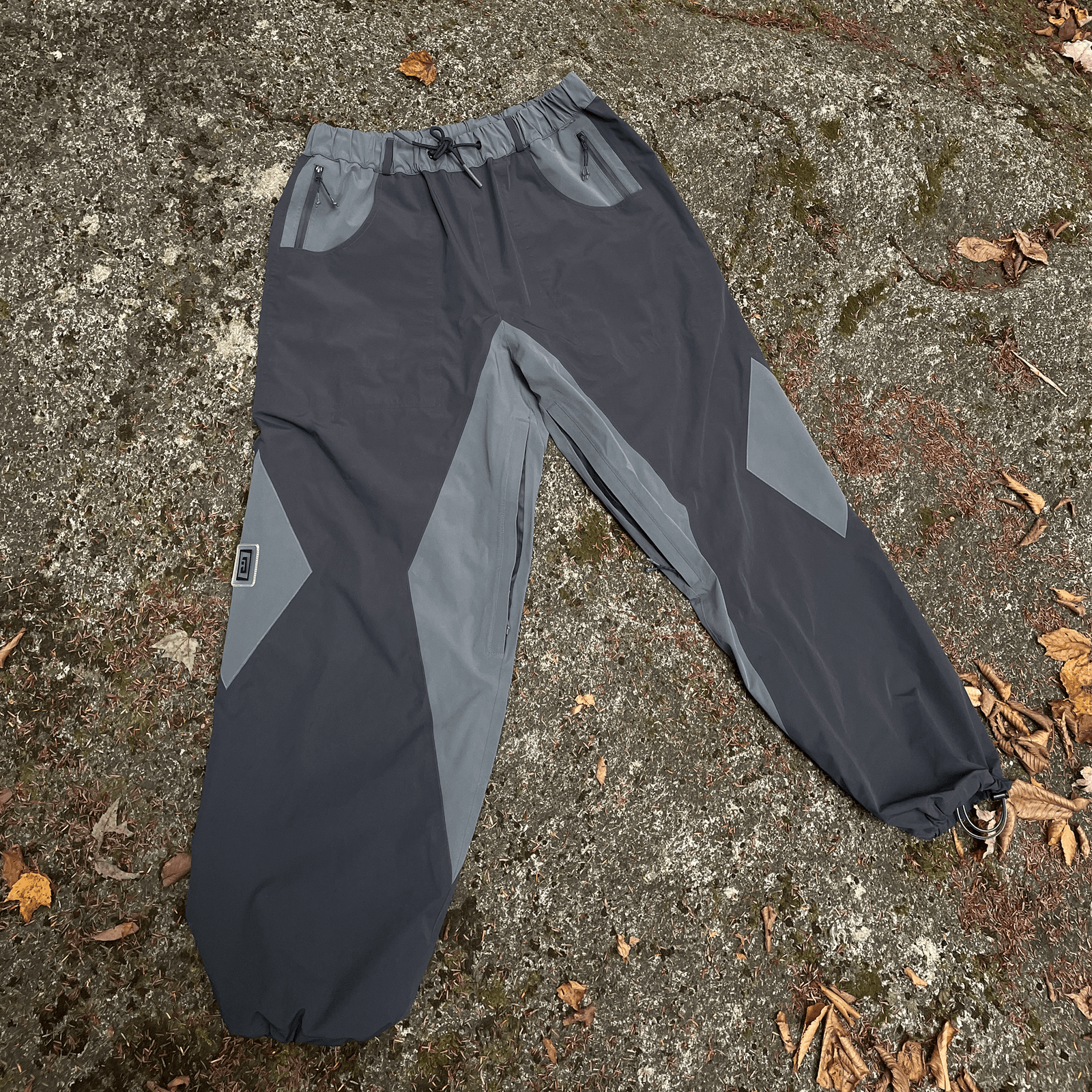 a pair of gray baggy snowpants with large leg vents, ankle cinches and zipper pockets